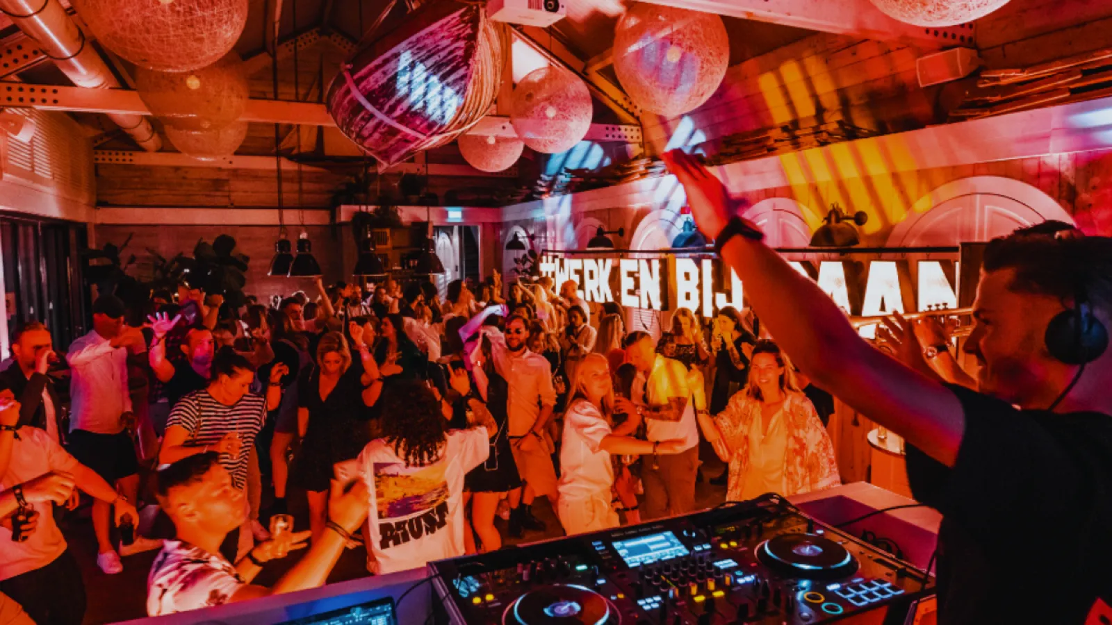 DJ achter de mengtafel met volle dansvloer tijdens een feest