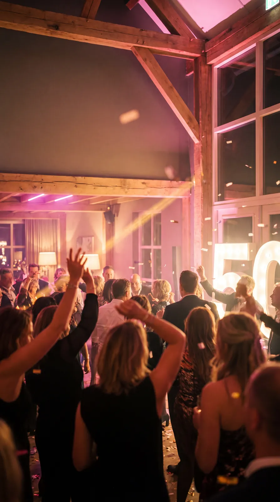 Feestende gasten met handen omhoog op de dansvloer