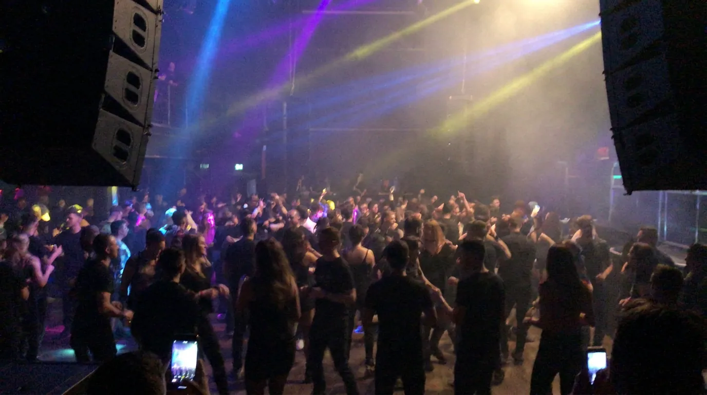 Grote dansvloer met line-array speakers en kleurrijke lichtshow
